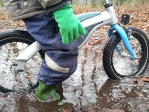 Jongetje op kinderfiets met regenkleding aan, Ouders van Nature.nl
