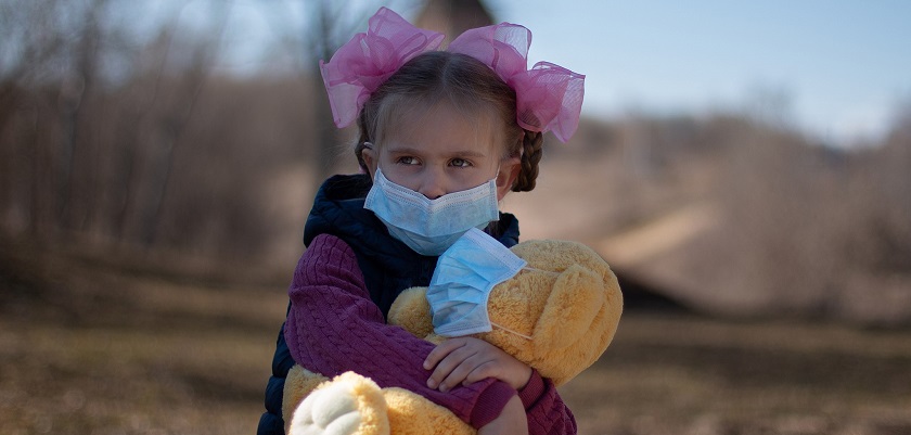 Kinderen kunnen erg bang zijn voor het coronavirus zoals dit meisje met mondmaster en teddybeer.