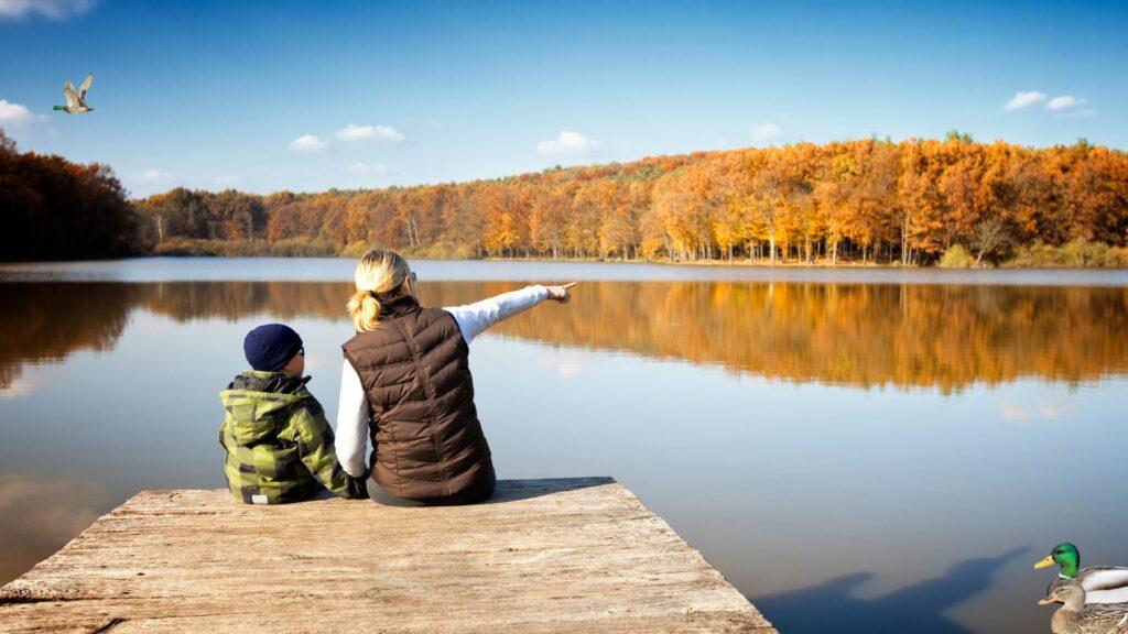 Moeder en kind kijken uit over een meer in de natuur.