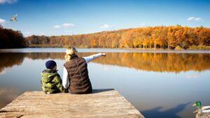 Moeder en kind kijken uit over een meer in de natuur.